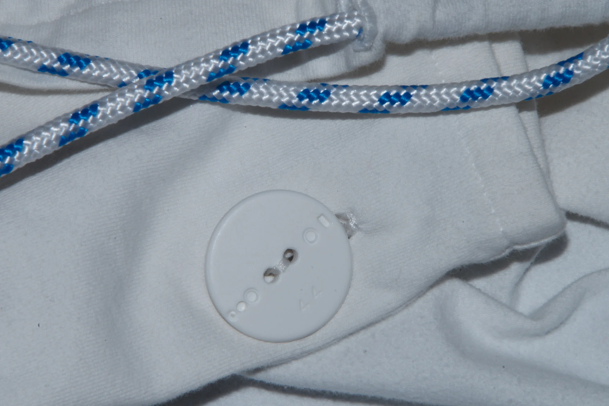 Botón blanco y cabo náutico azul y blanco sobre tejido crudo